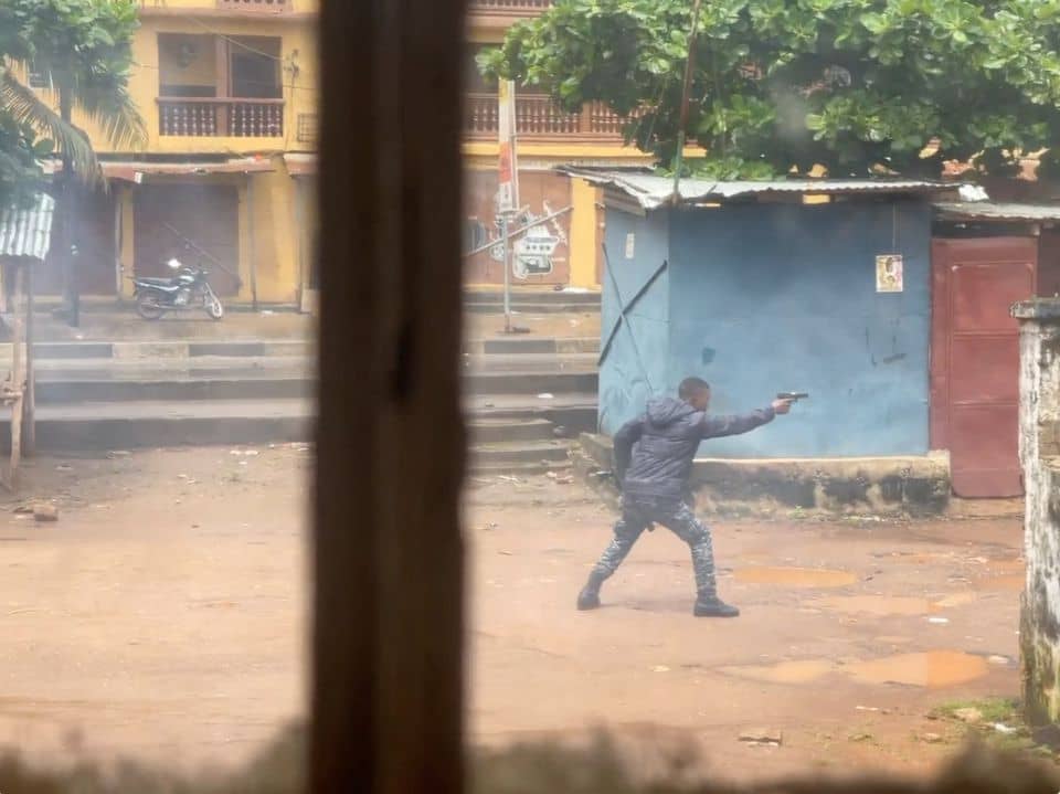 Screenshot from a social media video of a police officer aiming at protesters in Freetown